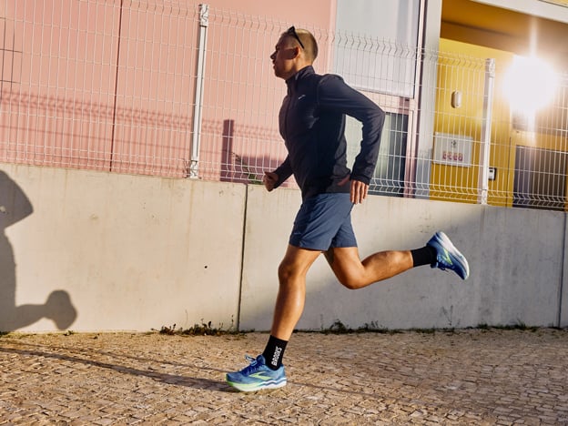 Long shot of a man wearing Brooks Running beanie and clothing on rocky track